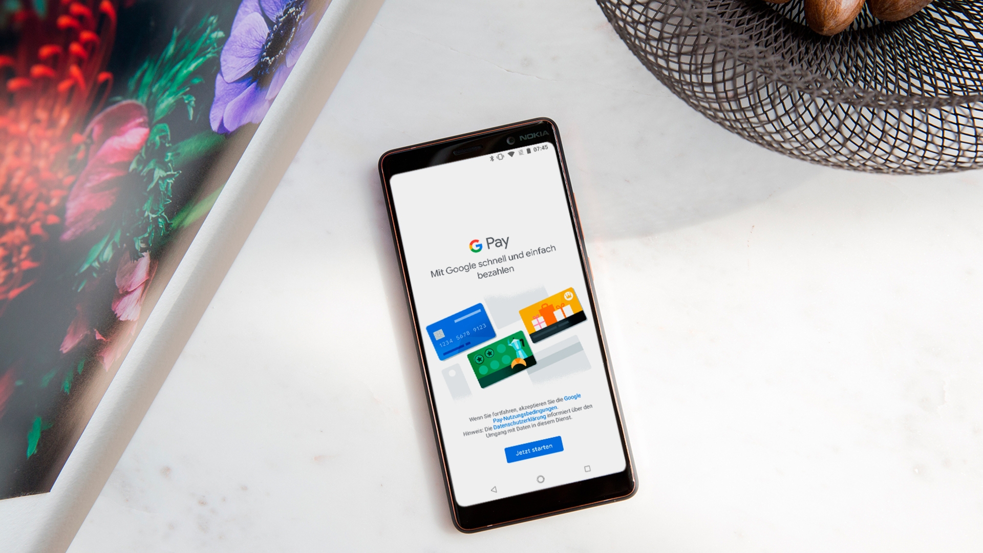 Smartphone mit geöffneter "Google Pay"-App auf einem weißen Tisch.