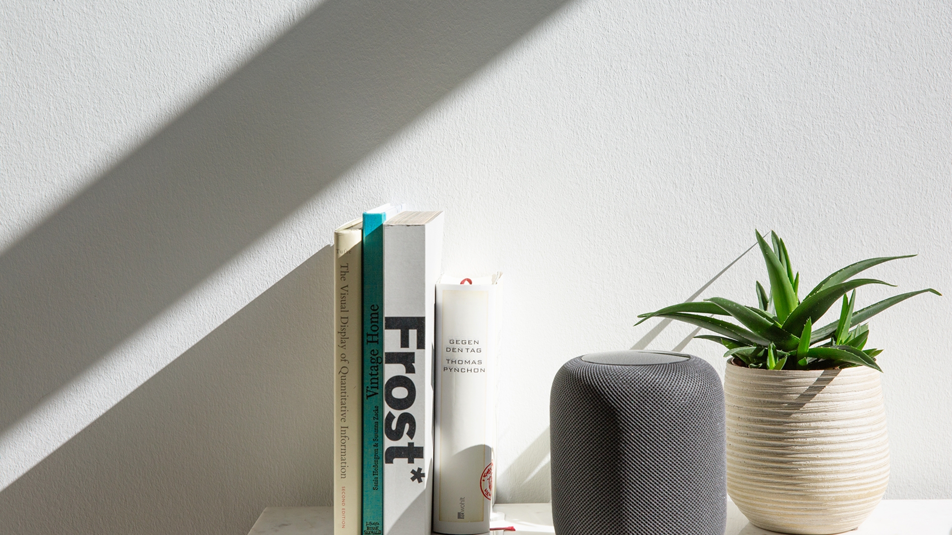 Der HomePod zwischen Büchern und einer Pflanze