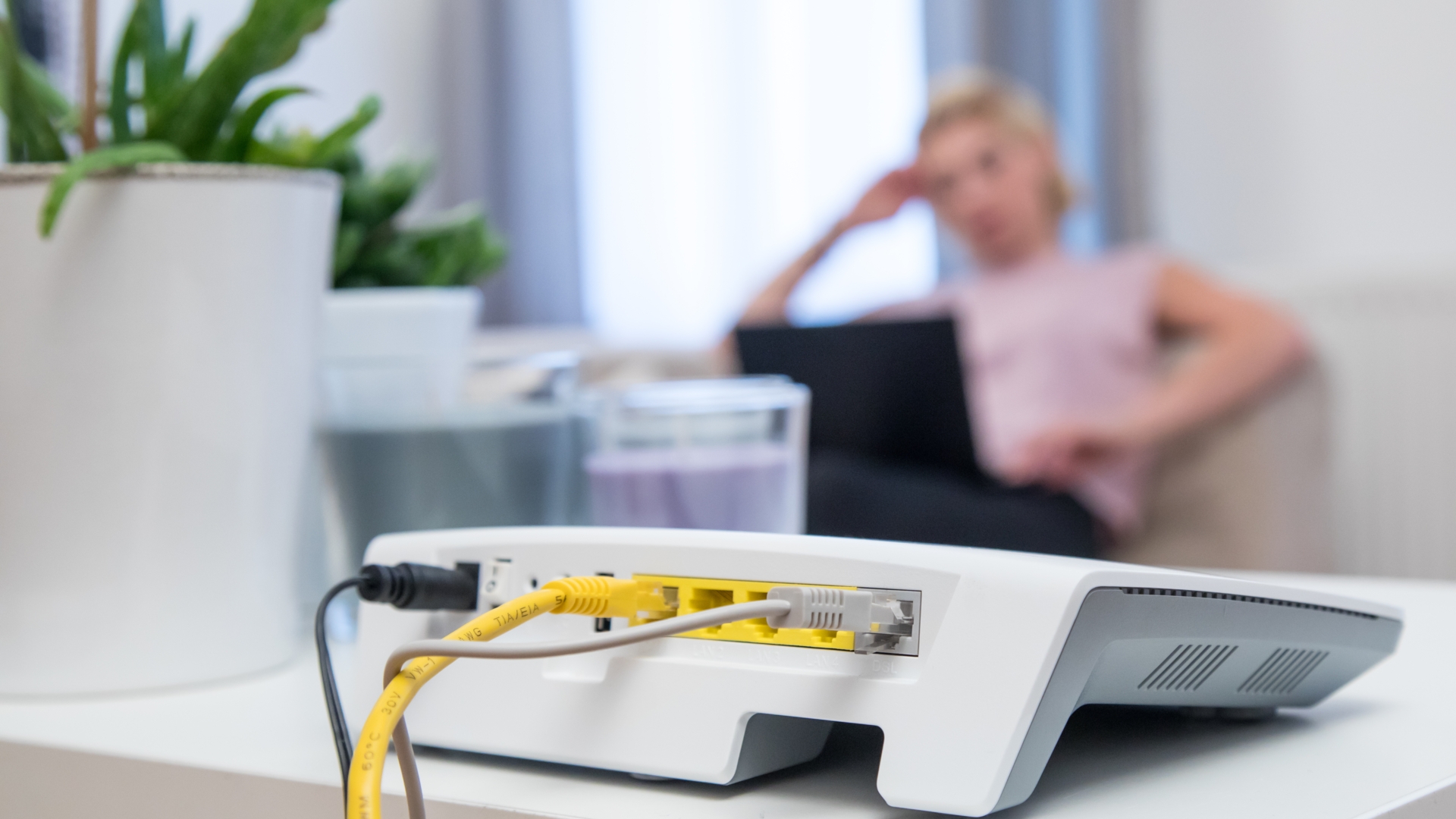 WLAN-Router liegt vor verärgerter Frau auf Tisch.