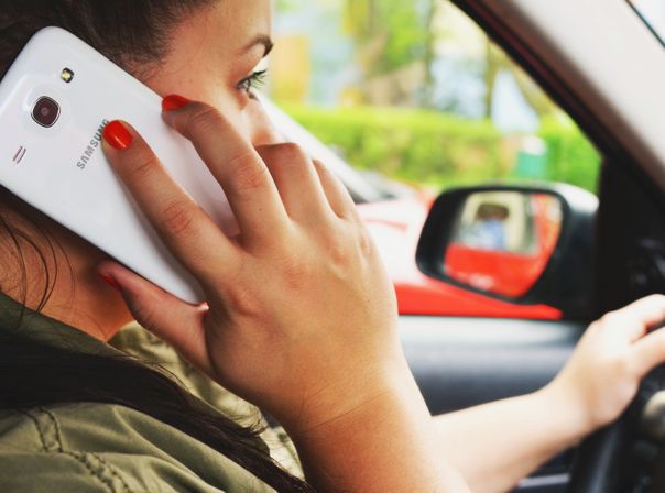 Frau mit Smartphone am Steuer