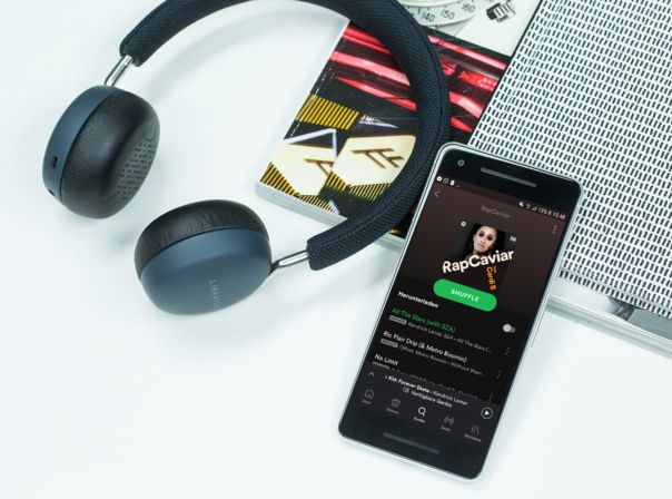 Smartphone mit Spotify App und Kopfhörer auf Tisch