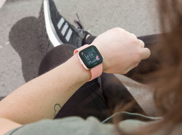 Fitbit Versa Frau schaut auf Smartwatch