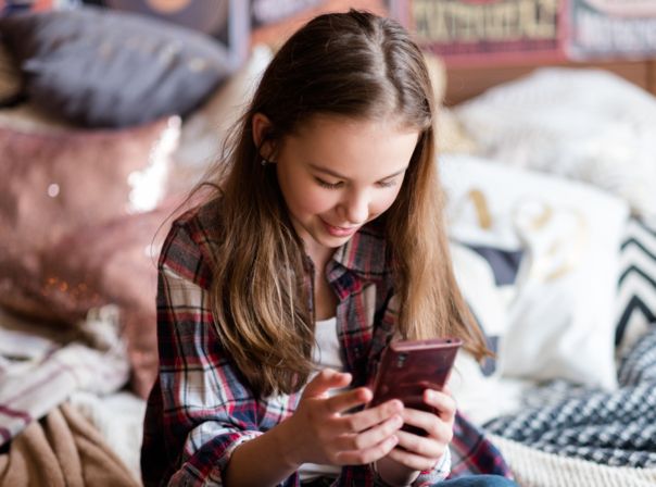 Kind schaut auf Smartphone in seinen Händen