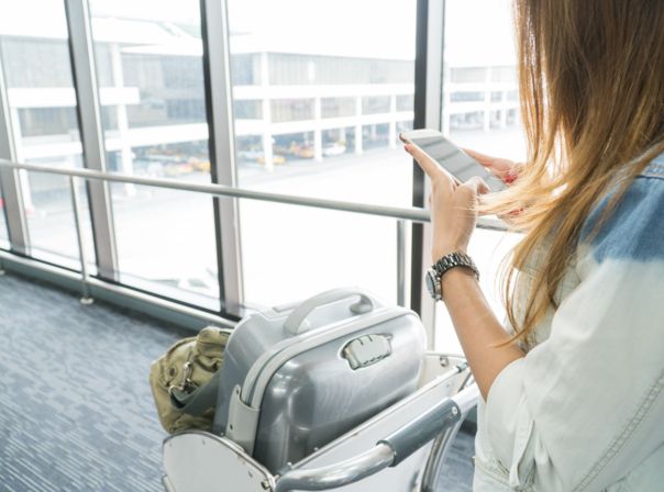 Frau wartet mit Koffer am Flughafen.