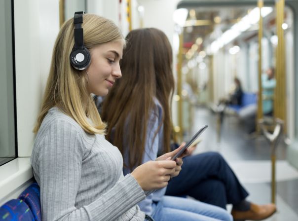 Junge Frau mit Kopfhörer und Tablet in der U-Bahn