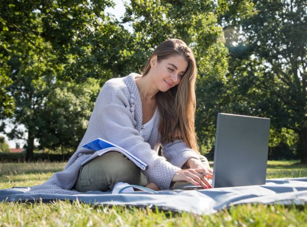 Eine junge Frau sitzt am 14.08.2019 in einem Park in Hamburg und lernt fuer eine Pruefung (gestellte Szene)