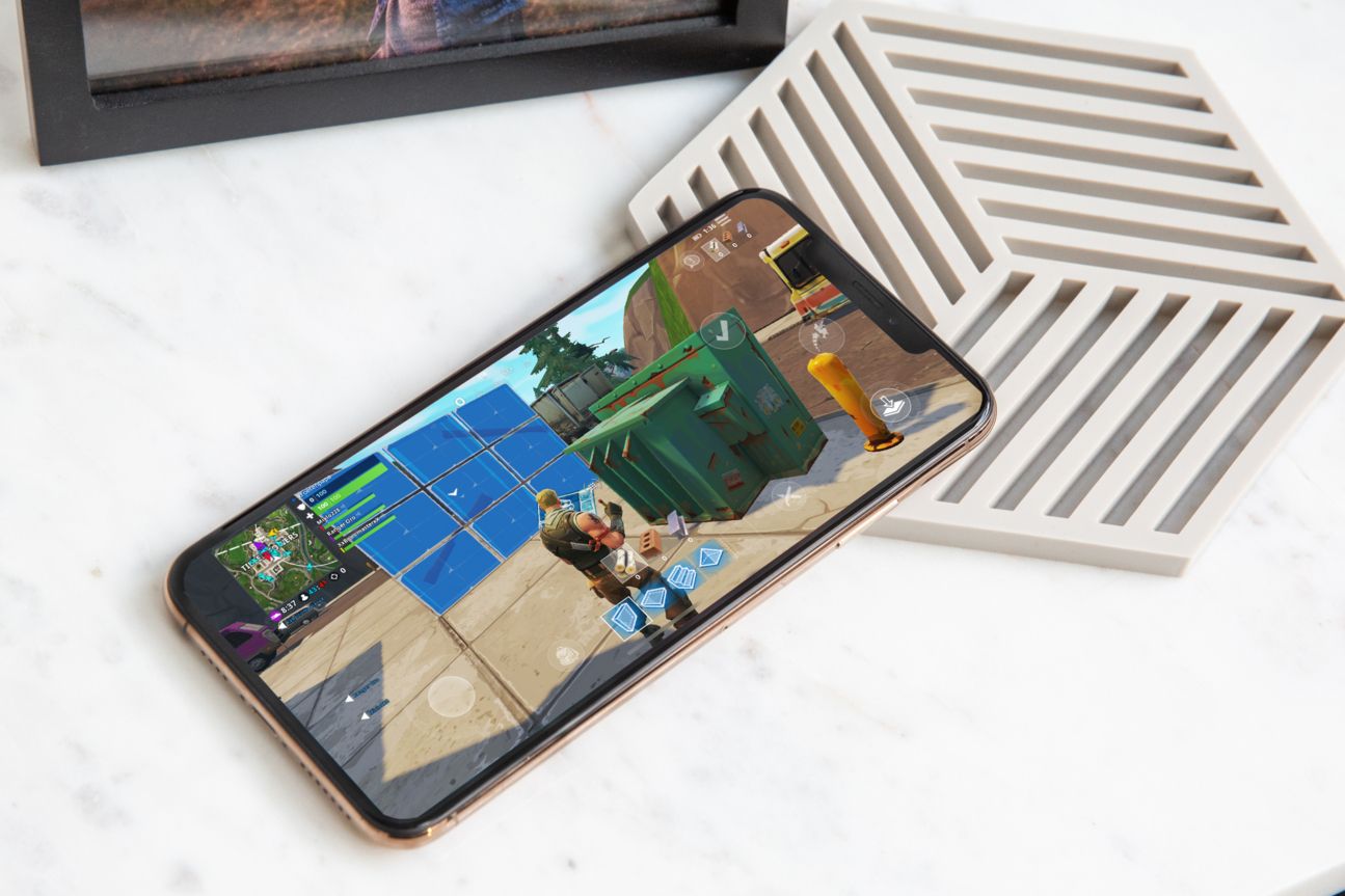 Fortnite auf dem iPhone Xs Max, das auf einer weißen Holzablage liegt.