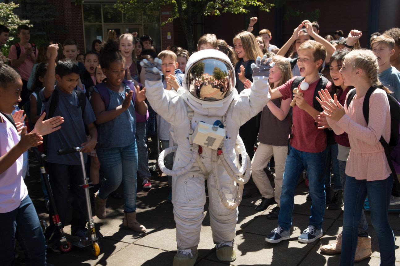 Junge im Astronautenanzug vor jubelnder Menge.