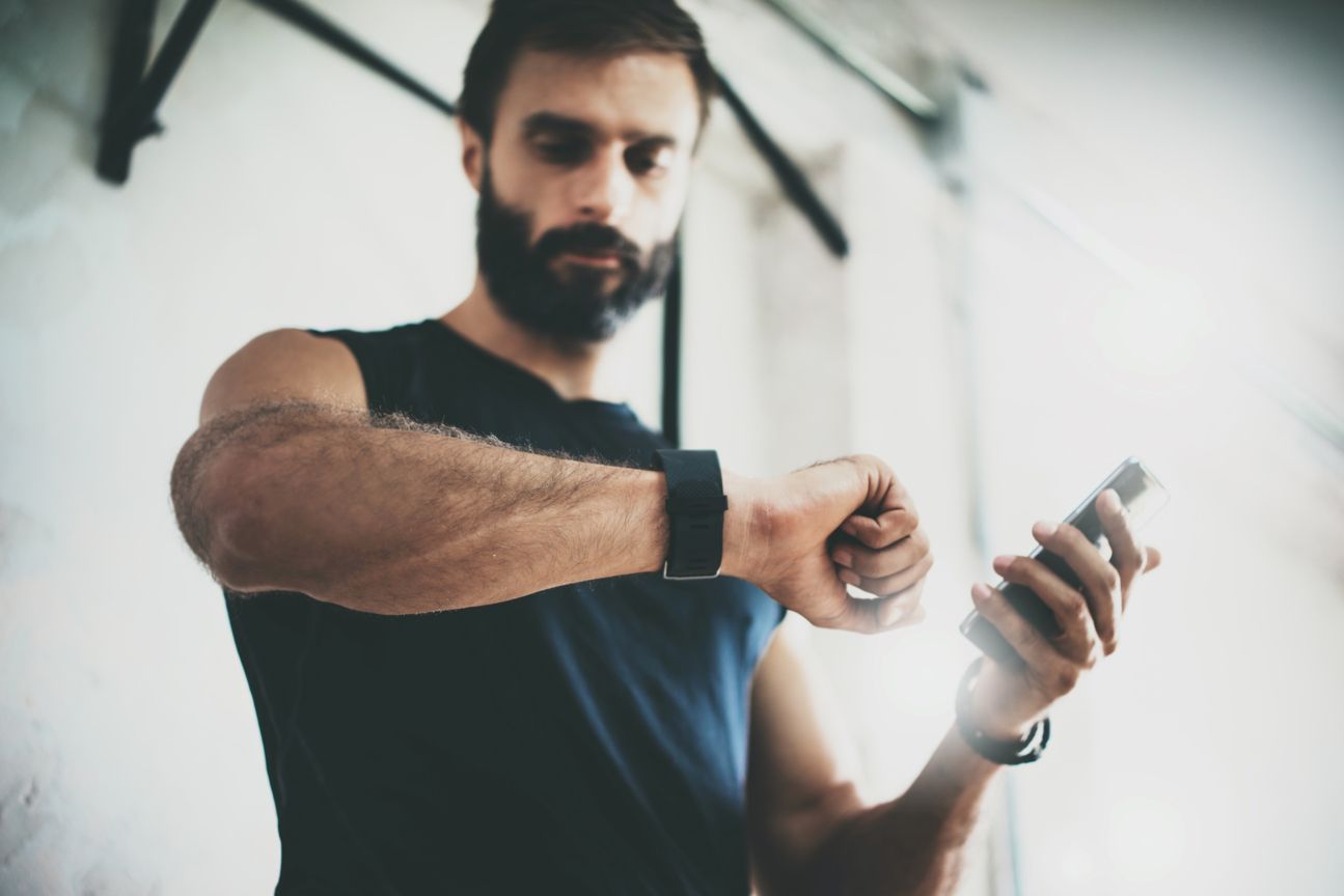 Sportler schaut auf Smartwatch.