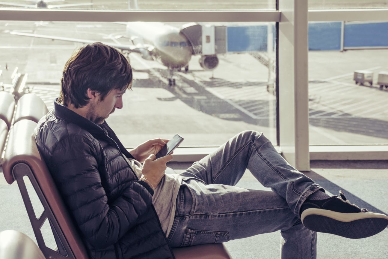 Mann mit Smartphone am Flughafen