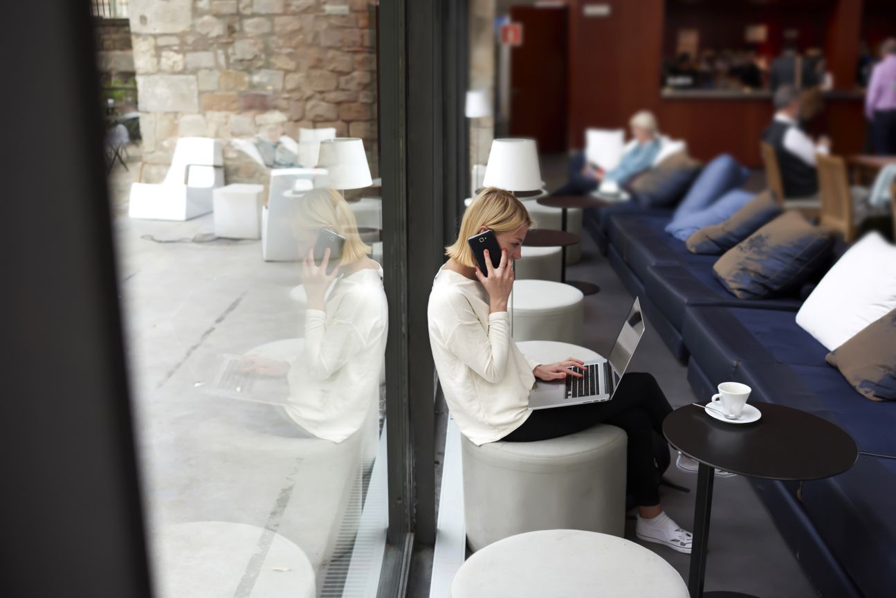 Businesswoman surft und telefoniert in der Hotellobby