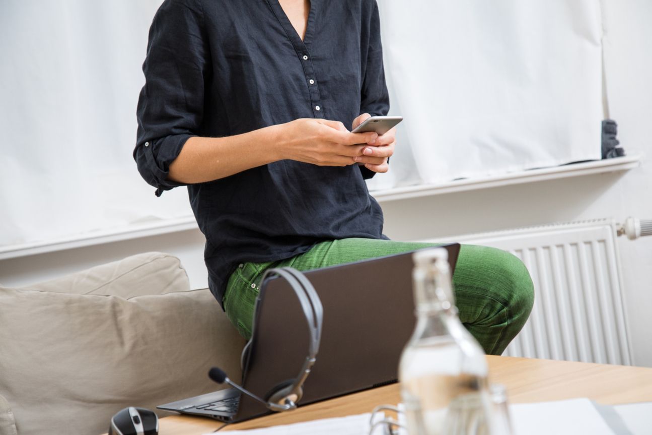 Frau mit Smartphone vor PC